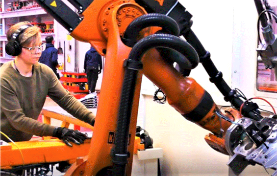 Operator working with robotic welding arm
